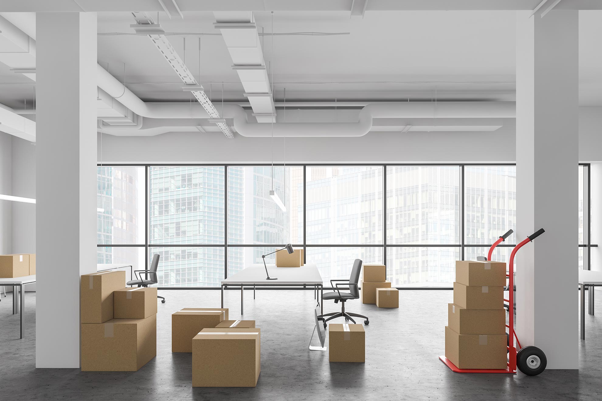 Ein nahezu leerer großer Büroraum im höher gelegenem Stockwerk, in denen Bürostühle, Tische und einige Umzugskartons stehen.